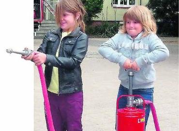 Amelie Arndt (l.) und Wolke Kleemann testen ihre Kräfte an der Kübelspritze.