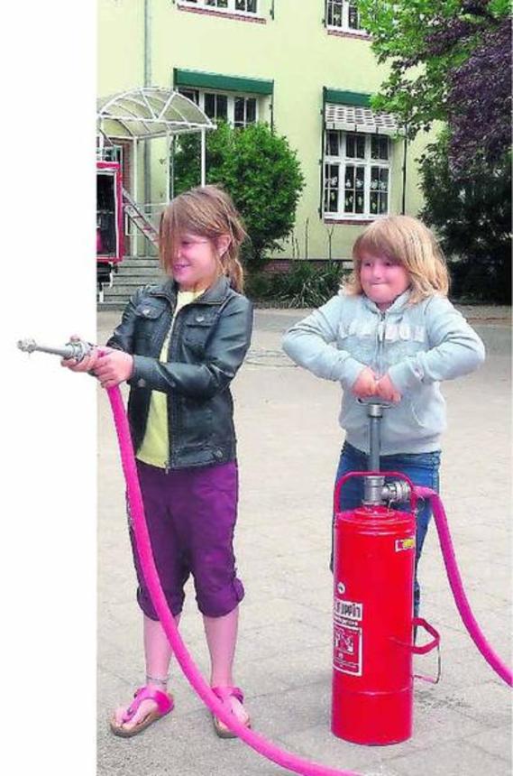 Amelie Arndt (l.) und Wolke Kleemann testen ihre Kräfte an der Kübelspritze.