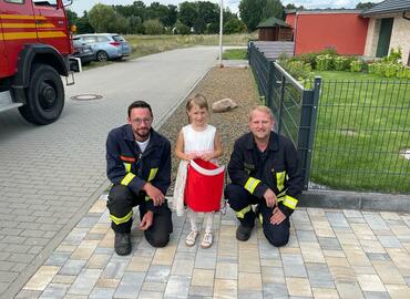 Kinderfeuerwehrwart Marcel Schiemenz und Stellvertretender Jugendfeuerwehrwart Louis Thom überbringen die Geschenke an eine Schulanfängerin